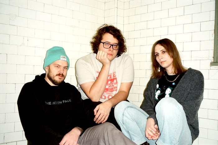 malamiko kneeling in the corner of a bathroom with tile walls. we are all staring blankly in various directions