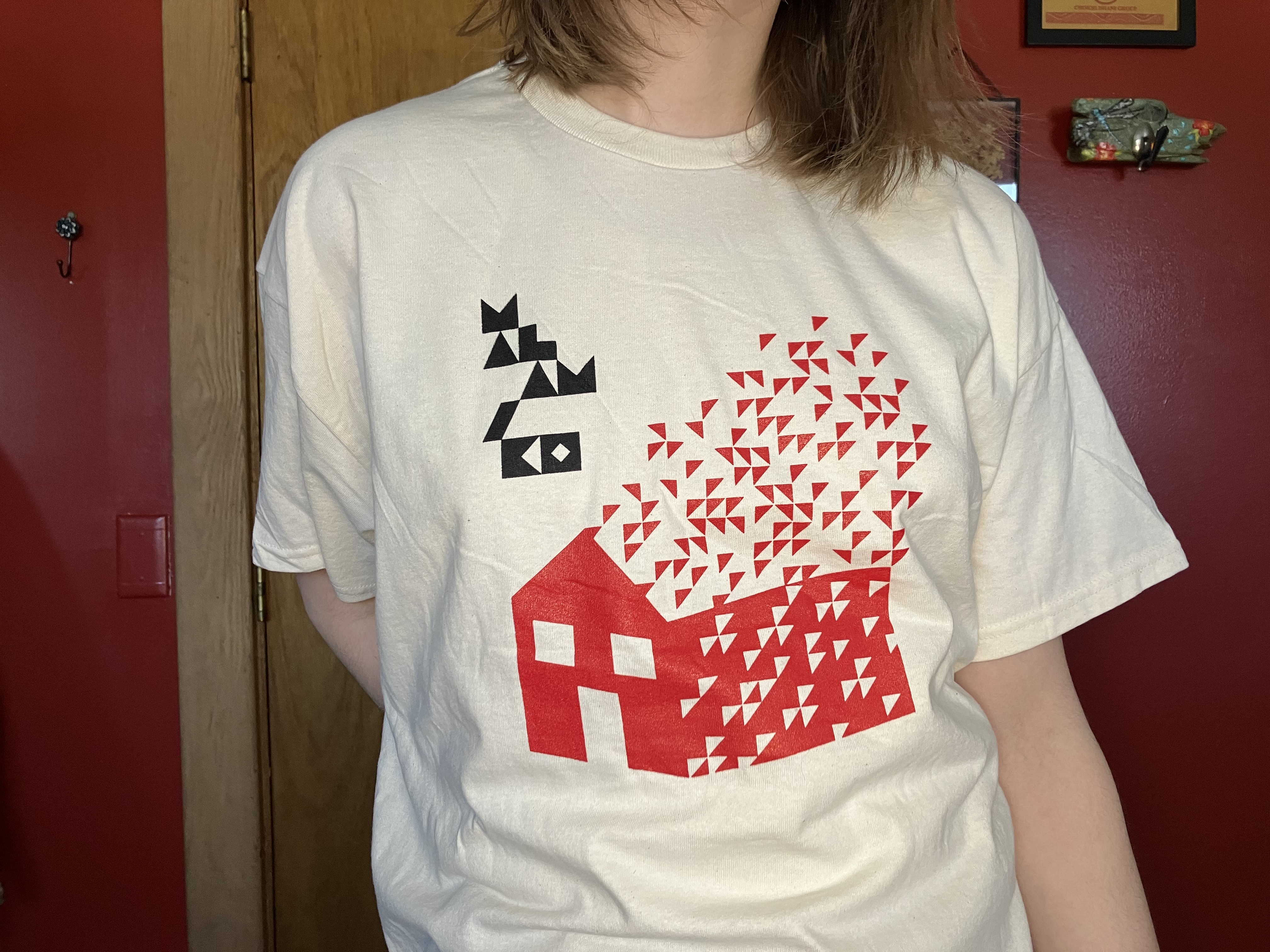 daisy wearing the new malamiko t-shirt designed by zack stewart - natural cotton with a red house with triangles coming out of the top to represent fire